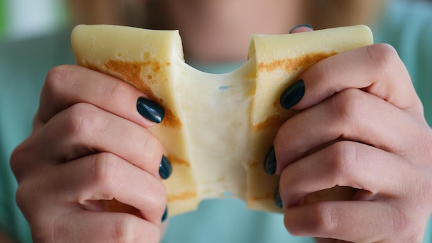 Une personne tient une crêpe de farine avec du fromage en gros plan