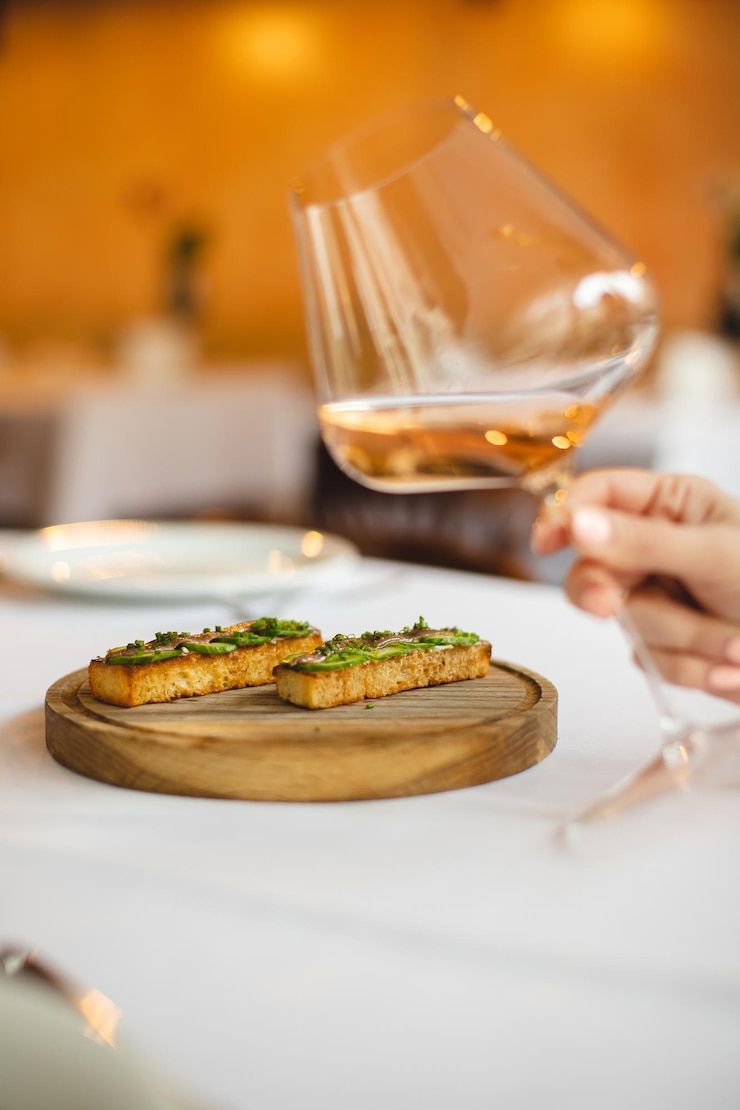 Photo une personne tient un verre à vin et un morceau de pain avec une tranche de pain avec une feuille verte dessus.