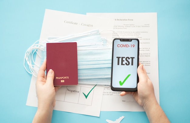 personne titulaire d'un passeport et d'un smartphone avec un test covid sur fond bleu avec des avions