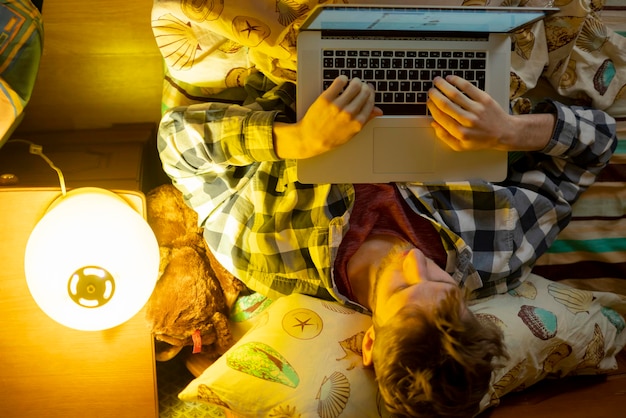 La personne travaille avec un ordinateur portable avant de dormir au lit b