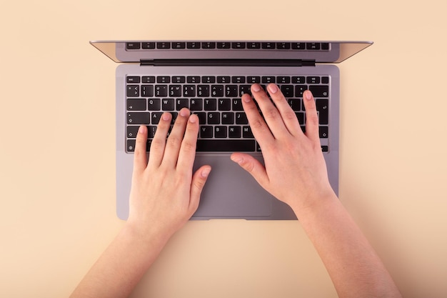 Personne utilisant un ordinateur portable sur fond beige Flatlay concept shopping et lieu de travail indépendant