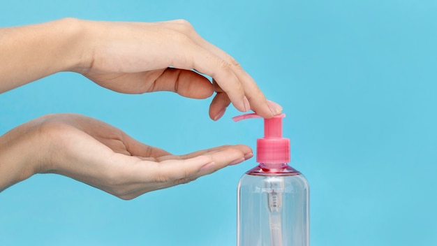 Photo personne utilisant un savon liquide à partir d'une bouteille rose