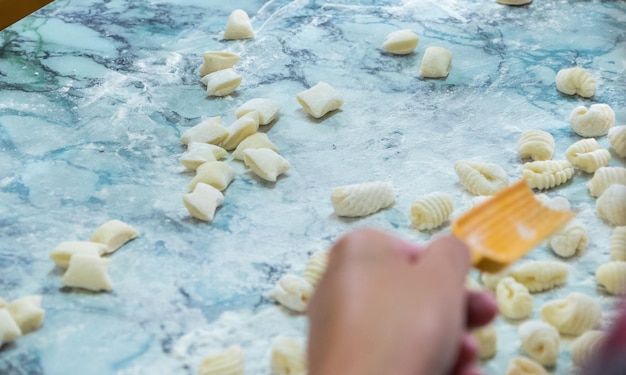 Une personne utilisant une spatule pour éplucher les pâtes sur une surface en marbre