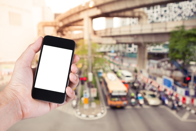 Photo personne utilisant le support d'écran blanc du smartphone sur place avec un bourdonnement d'embouteillage sur la rue de la ville à bangkok en thaïlande.