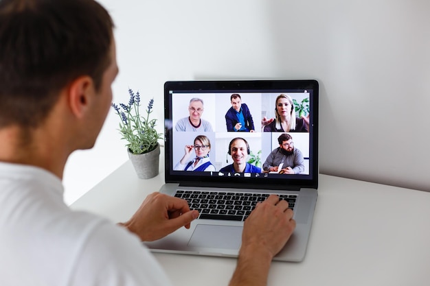 Personne utilisant la technologie de vidéoconférence dans la cuisine pour un appel vidéo avec des collègues à la maison et au bureau