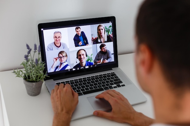 Personne utilisant la technologie de vidéoconférence dans la cuisine pour un appel vidéo avec des collègues à la maison et au bureau