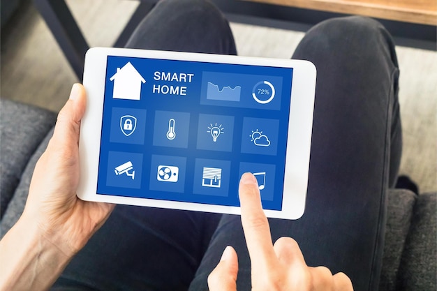 Une personne utilise une tablette avec une maison intelligente dessus.