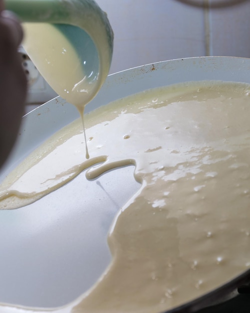 Une personne versant du liquide dans un bol de pâte.