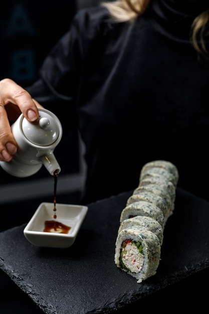 Une personne versant de la sauce dans un bol de sushi