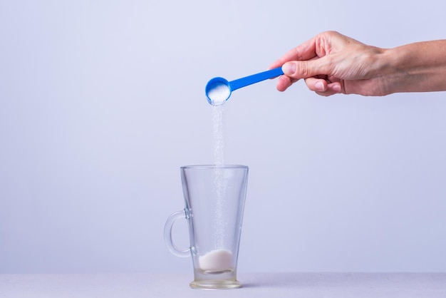 Une personne verse du sucre dans un verre