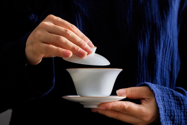 Une personne verse une tasse de thé dans une tasse blanche.