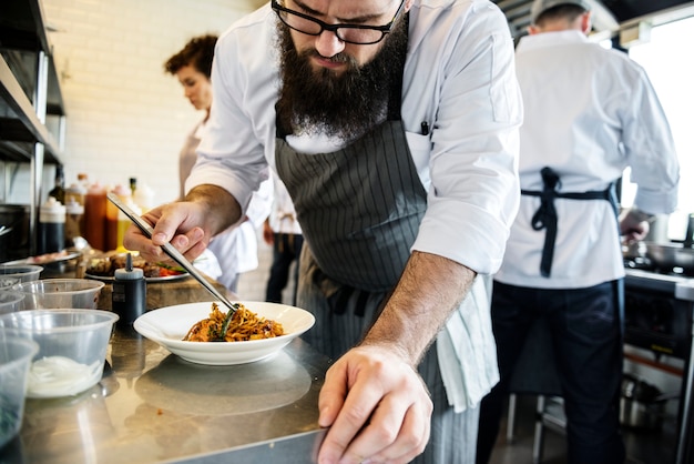 Personnel de cuisine décorant un plat cuisiné