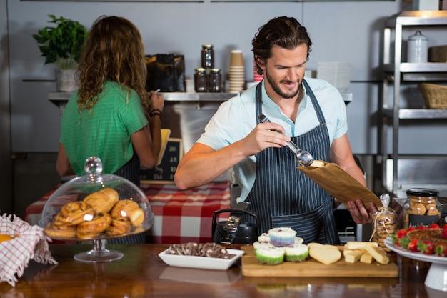 Personnel emballant un gâteau dans un sac en papier au comptoir