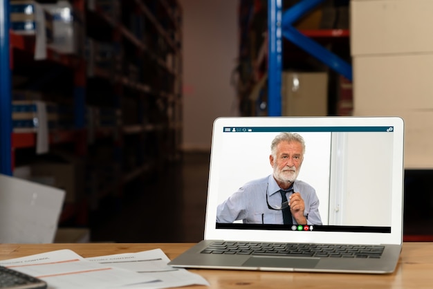 Personnel d'entrepôt parlant par appel vidéo sur un écran d'ordinateur dans un entrepôt de stockage