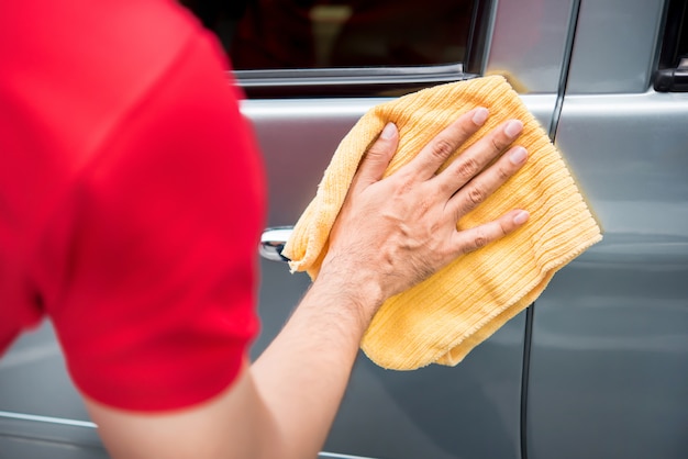 Personnel d'entretien automobile masculin, nettoyage de la porte de voiture avec un chiffon microfibre
