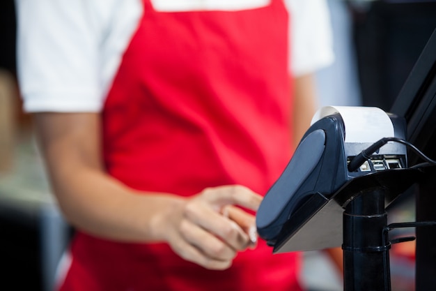 Personnel féminin à l'aide d'un terminal de carte de crédit au comptoir caisse