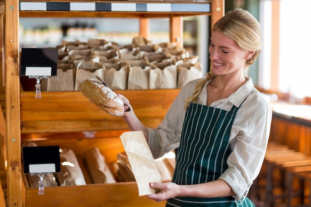 Personnel féminin emballant un pain dans un sac en papier