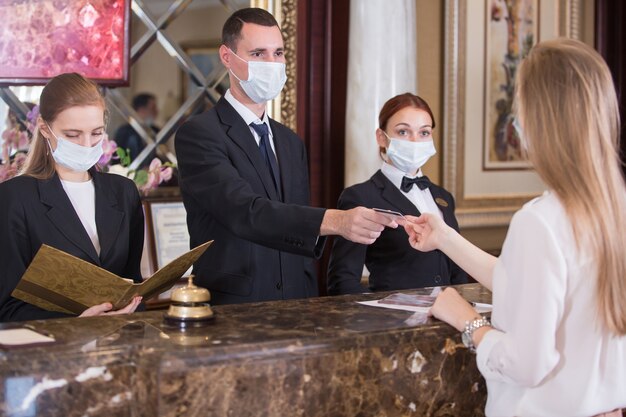 Le personnel de l'hôtel sert les clients dans des masques médicaux