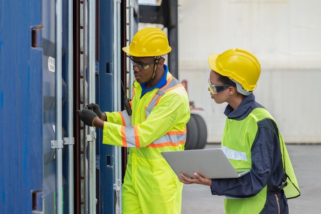 Le personnel logistique de l'entrepôt utilise un ordinateur portable pour vérifier les produits dans la boîte de conteneurs lors de l'expédition de conteneurs de fret