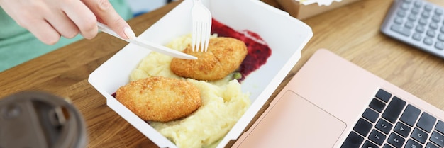 Personnel mangeant des escalopes avec de la purée de pommes de terre dans des boîtes en carton en gros plan de bureau