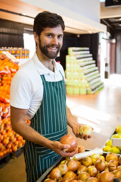 Personnel masculin organisant des fruits dans la section biologique du supermarché