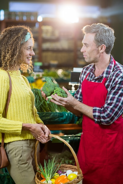 Personnel masculin souriant aidant une femme à faire l'épicerie