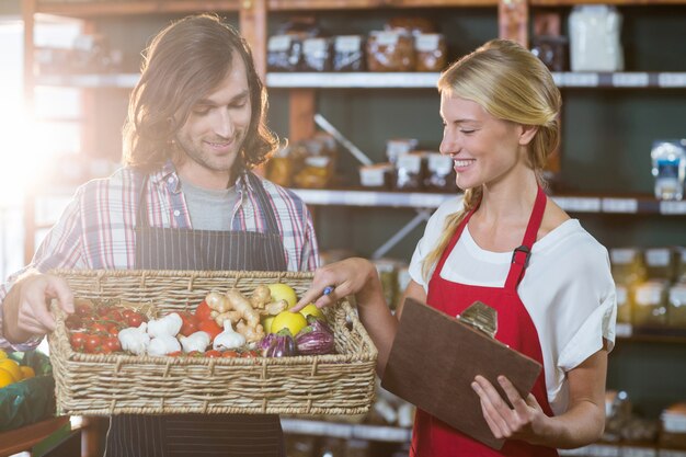 Personnel masculin tenant panier de légumes et personnel féminin avec presse-papiers