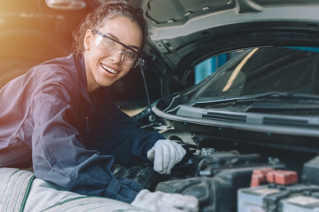 Personnel mécanicien vérifiant le concept de moteur de voiture Femme intelligente et forte travaillant dans un garage automobile