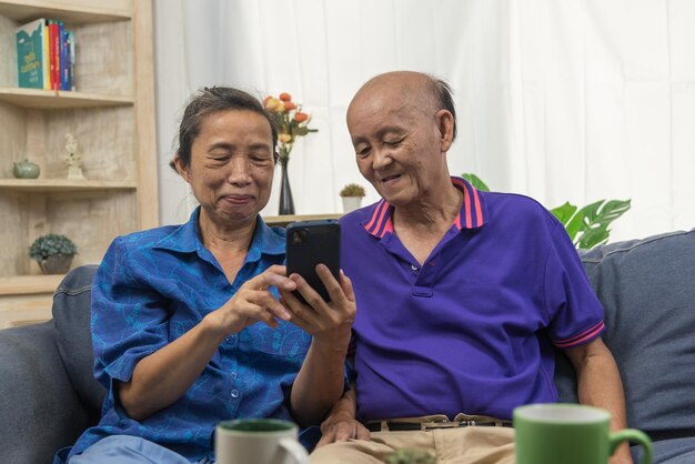 Personnes âgées asiatiques utilisant la technologie de communication Internet en ligne de connexion de téléphone portable à la maison