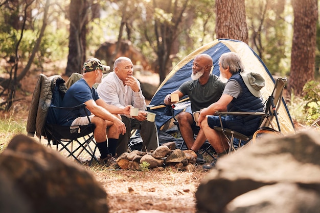 Des personnes âgées campent et se détendent dans la nature pour un voyage d'aventure ou des vacances d'été ensemble sur des chaises près d'une tente dans la forêt