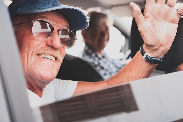 Personnes âgées conduisant avec une voiture homme âgé avec des moustaches agitant la main pour saluer quelqu'un Concept de voyage et de vacances