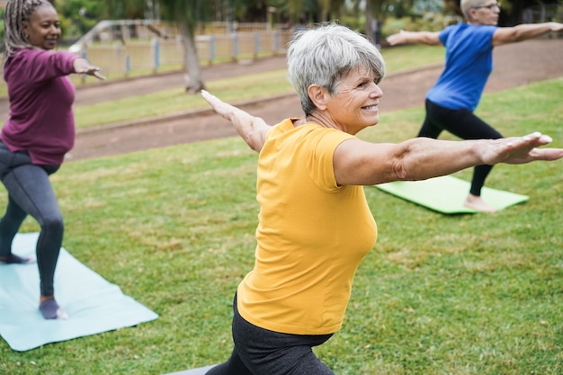 Personnes âgées faisant du yoga en gardant la distance au parc de la ville - Focus sur le visage de la femme centrale