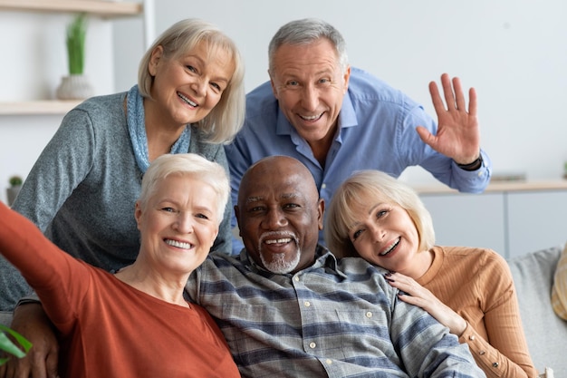 Personnes âgées heureuses prenant selfie ensemble intérieur de la maison