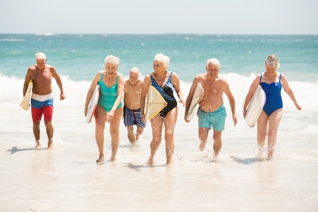 Personnes âgées tenant des planches de surf à la plage