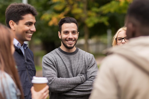 personnes, amitié, communication et concept international - groupe d'amis heureux marchant le long du parc d'automne et buvant du café