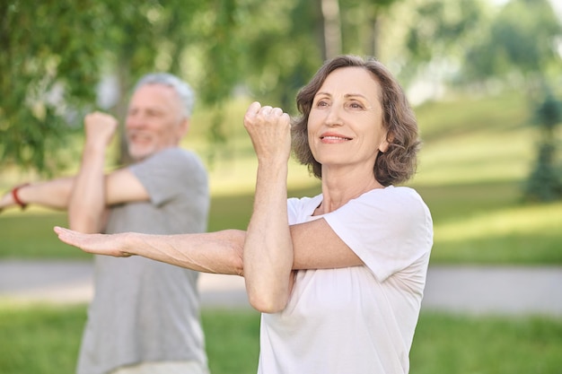 Personnes ayant un cours de yoga dans le parc et étirant leurs bras