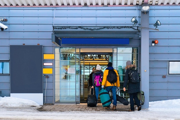 Personnes avec des bagages à l'entrée de l'aéroport de Rovaniemi en hiver