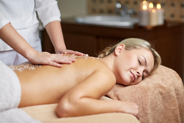 personnes, beauté, spa, mode de vie sain et concept de relaxation - gros plan d'une belle jeune femme allongée les yeux fermés et ayant un massage au sel l dans le spa