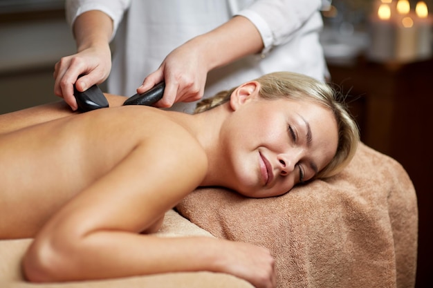 personnes, beauté, spa, mode de vie sain et concept de relaxation - gros plan d'une belle jeune femme ayant un massage aux pierres chaudes au spa