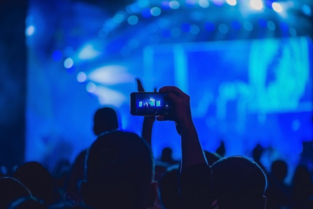 Personnes bénéficiant d'un concert de rock et prenant des photos avec un téléphone portable au festival de musique