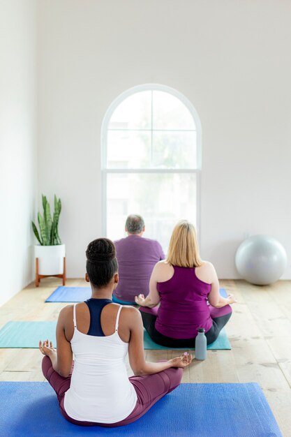 Personnes en bonne santé faisant une pose de yoga Sukhasana en cours de yoga