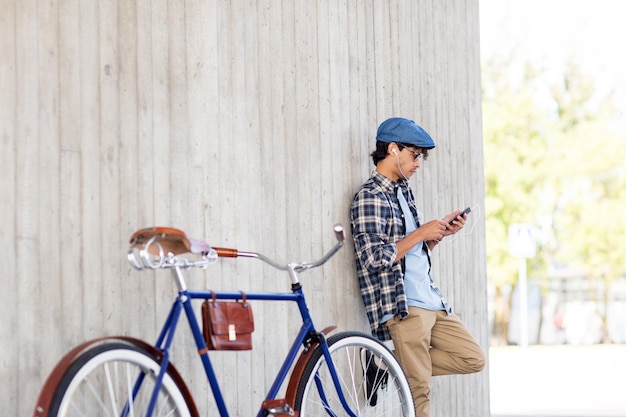 personnes, communication, technologie et style de vie - homme hipster avec smartphone, écouteurs et vélo à pignon fixe écoutant de la musique dans la rue de la ville