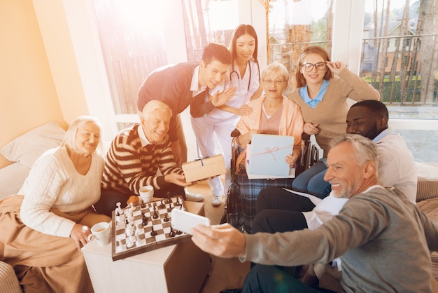 Des personnes dans une maison de retraite font un selfie avec une femme âgée