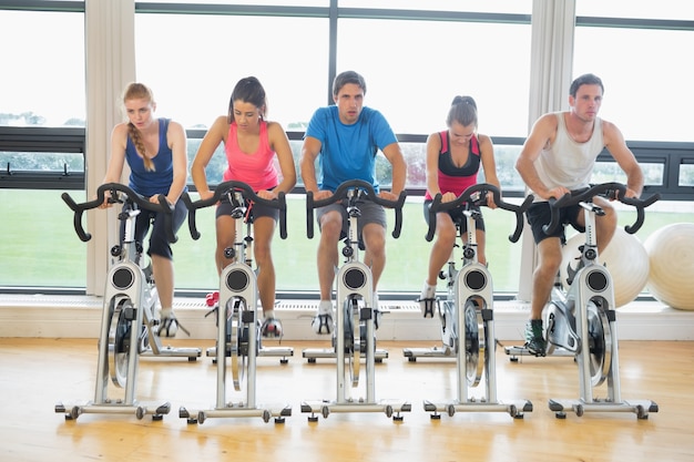 Personnes déterminées travaillant à la classe de spinning dans la salle de gym