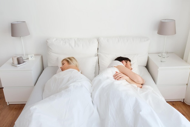 personnes, difficultés relationnelles, conflits et concept de famille - couple dormant dos à dos dans son lit à la maison