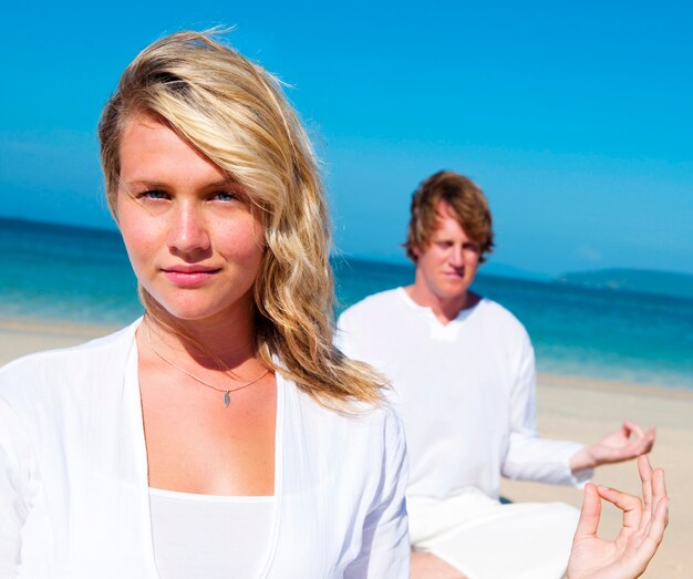 Les personnes effectuant le yoga sur la plage.