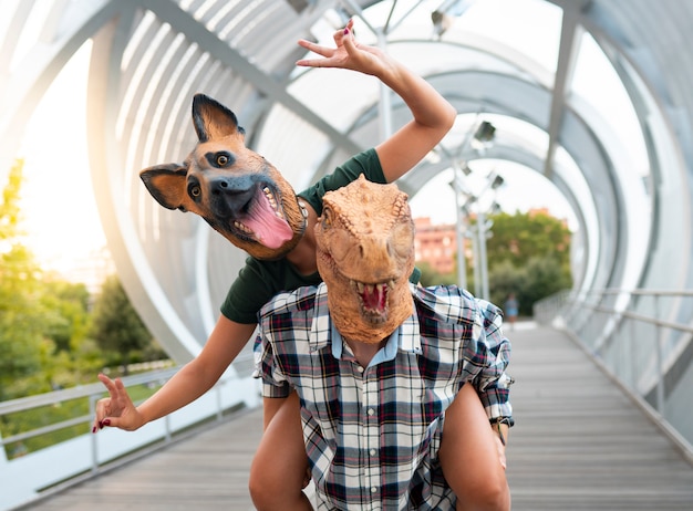 personnes élégantes couple de mode portant t-rex et masque de chien