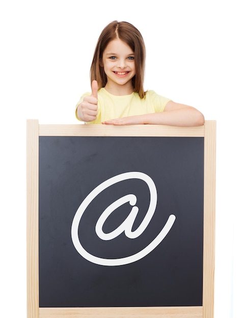 personnes, enfance, geste et concept internet - petite fille souriante avec tableau noir montrant les pouces vers le haut