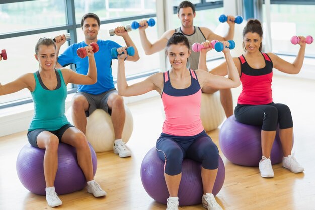 Personnes exerçant avec des haltères sur des ballons de remise en forme