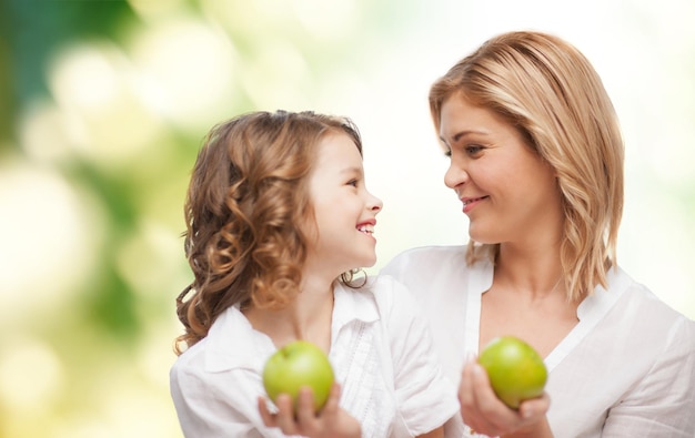 personnes, famille, alimentation saine et concept parental - heureuse mère et fille avec des pommes sur fond vert